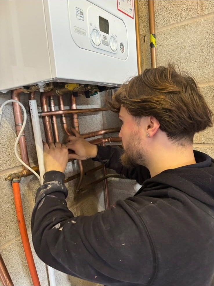 Cruz working on the copper pipework under a boiler