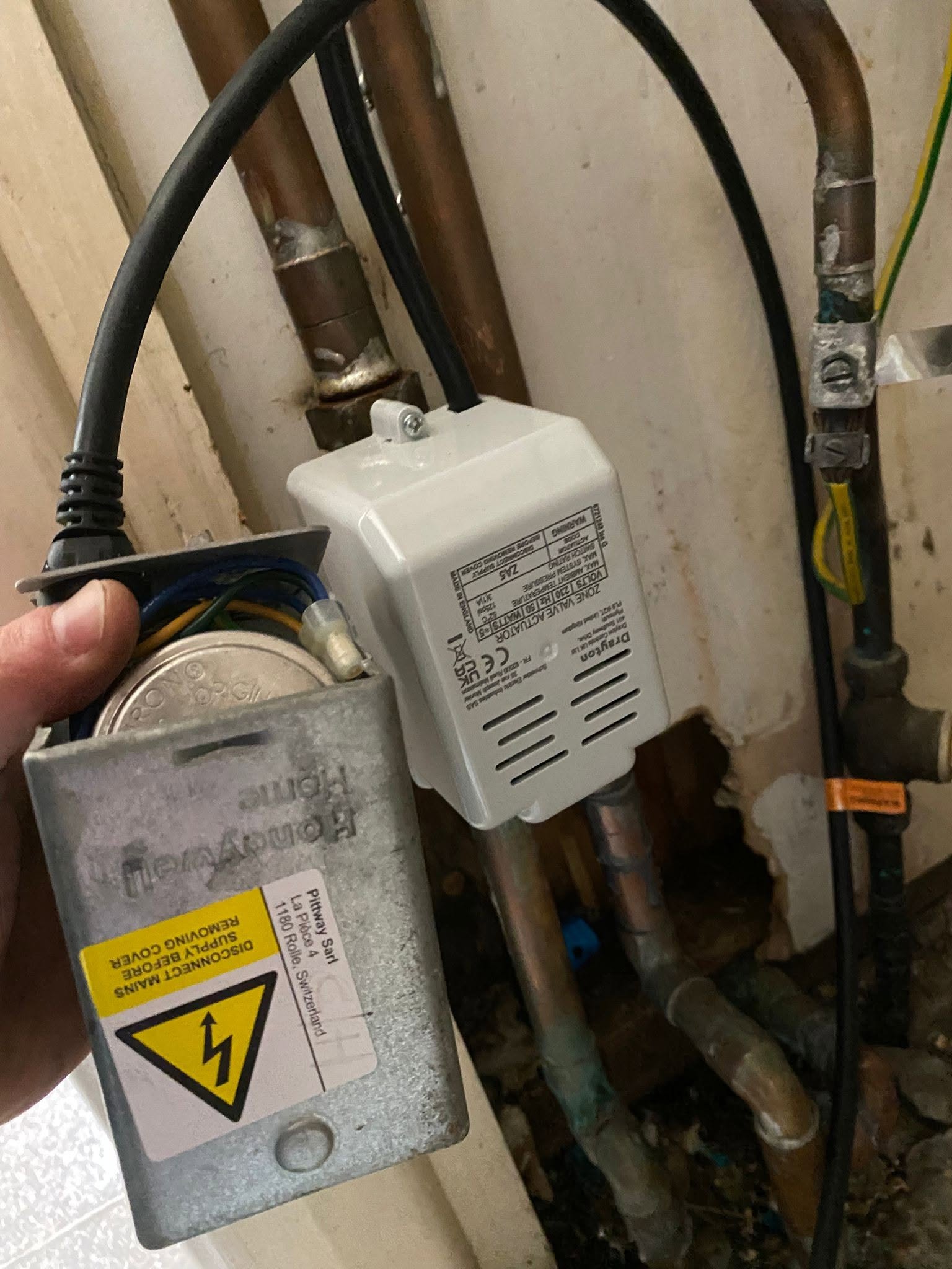 An old control unit held in a hand after being taken off the pipework