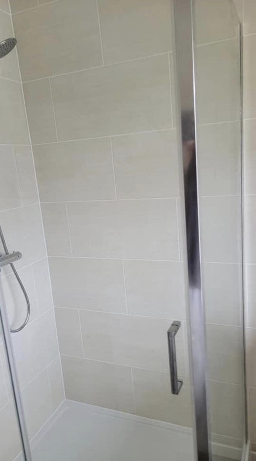 A finished shower enclosure with pale wall tiles