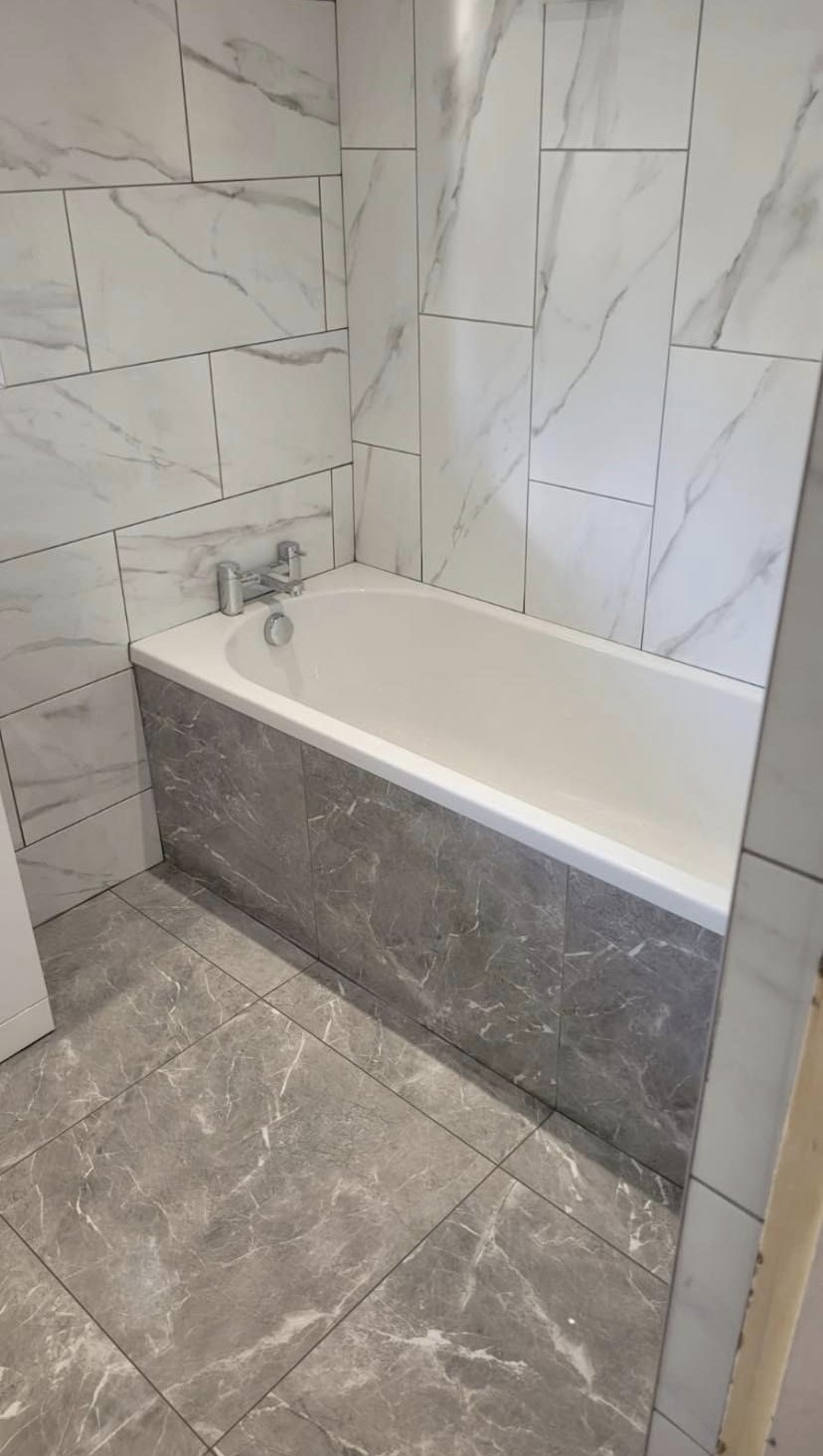 The finished bathroom with a grey marble-effect bath panel and floor