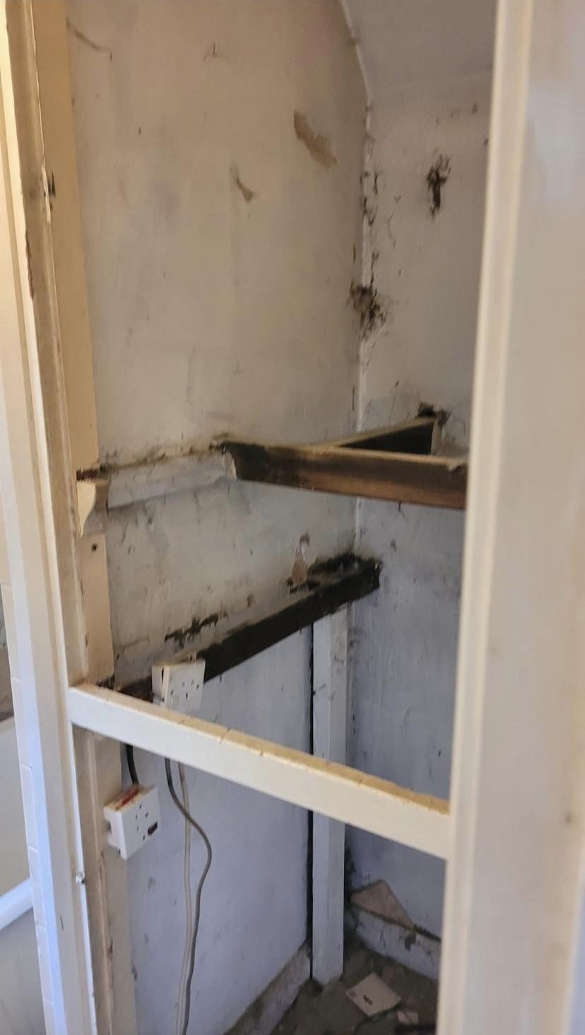 A bathroom corner stripped back to the bare wall, old brackets still on it