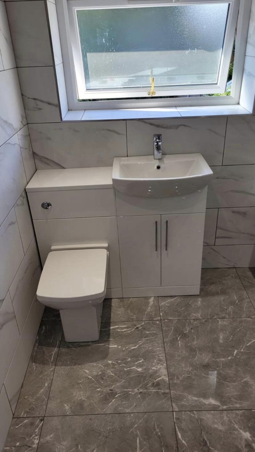 A WC and basin unit on a grey marble-effect floor