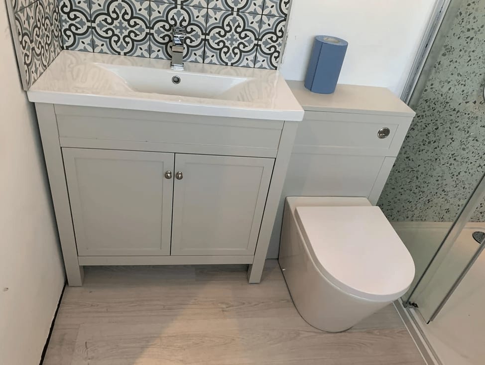 A grey shaker-style vanity unit with a patterned tile splashback and a back-to-wall WC