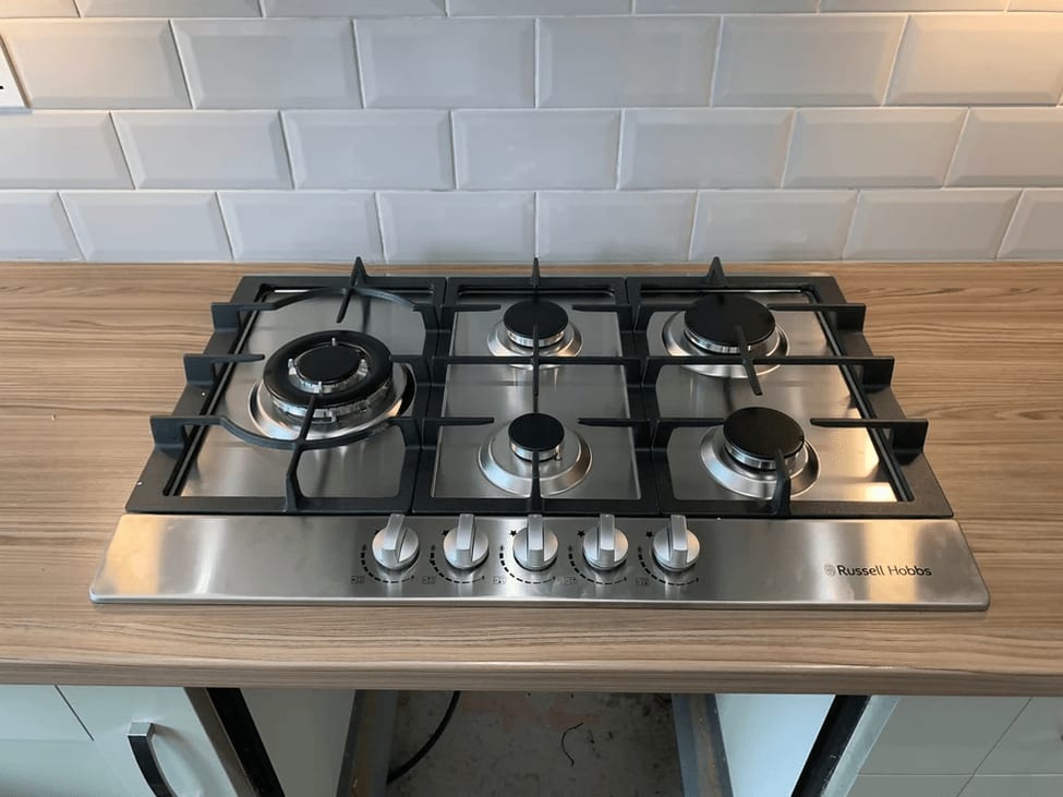 A five-burner stainless gas hob fitted into a wood-effect worktop